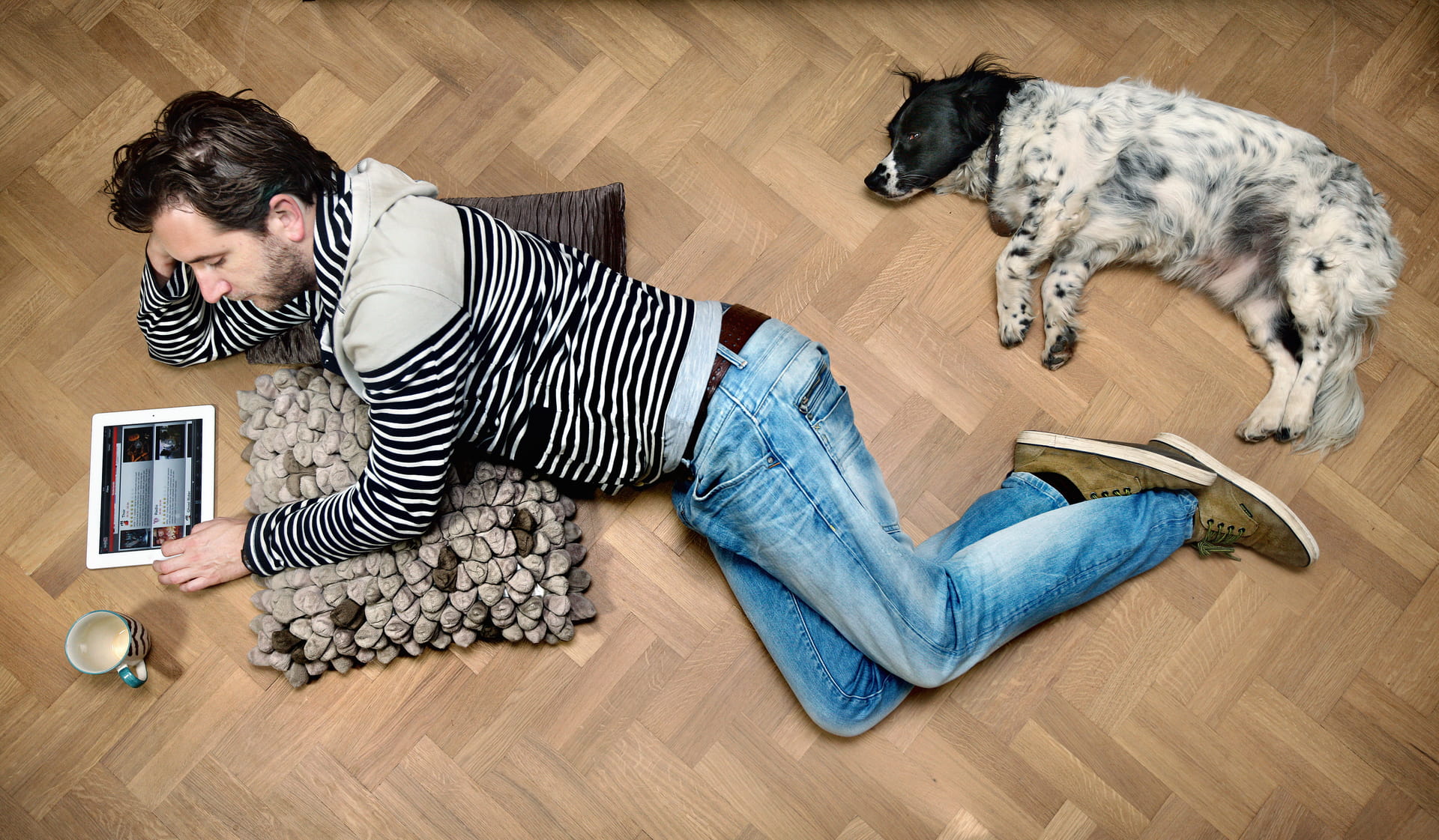 Man met tablet en hond liggend op grond Man met tablet en hond liggend op grond